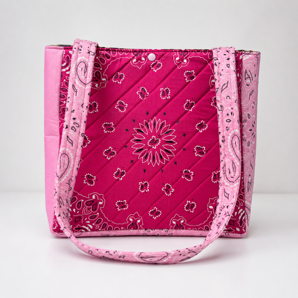 Hot pink handmade tote bag with bandana print, diagonal quilting, and snap closure.